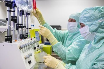 Lab employees in full personal protective equipment handling cell and gene therapy products.