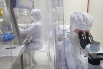 Two cell and gene therapy researchers in full personal protective equipment sat down in SCTbio’s clean room facility.